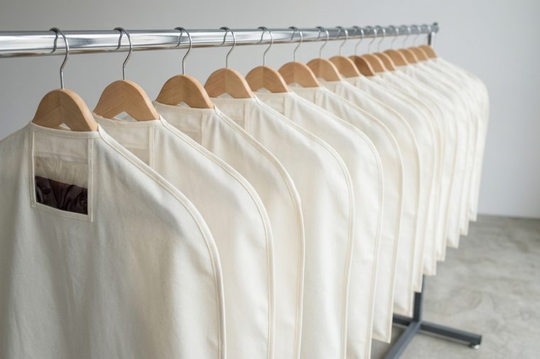 Housses de vêtements ivoire suspendues sur un portant chromé